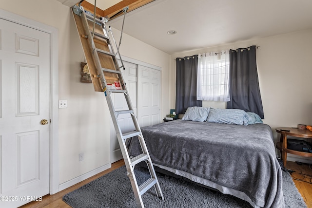 bedroom with wood finished floors, baseboards, and a closet