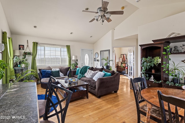 living area featuring high vaulted ceiling, light wood-style flooring, and a ceiling fan