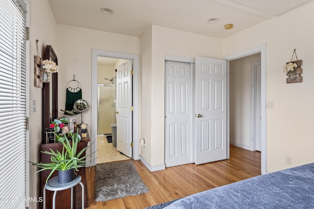 bedroom featuring ensuite bath, light wood-style flooring, and baseboards