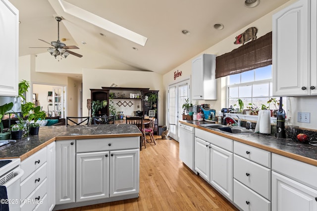 kitchen with light wood-style flooring, a sink, tile countertops, white appliances, and a peninsula