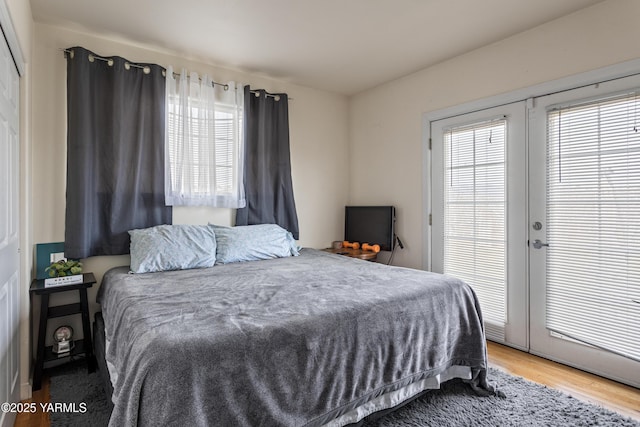 bedroom with french doors, wood finished floors, and access to outside