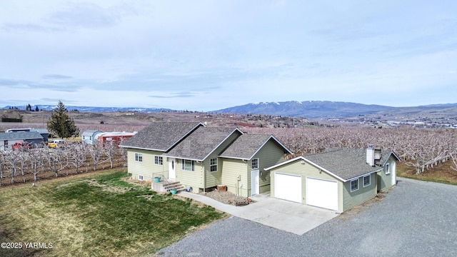 ranch-style house featuring entry steps, a mountain view, a shingled roof, a garage, and a chimney