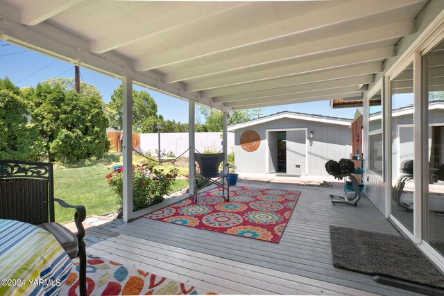 deck with an outdoor structure, a lawn, and fence