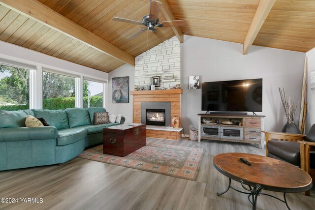 living room featuring wood ceiling, wood finished floors, beamed ceiling, a stone fireplace, and high vaulted ceiling