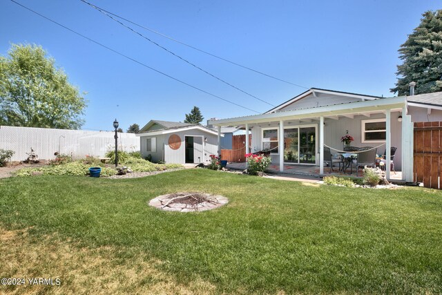 back of property featuring a yard, an outdoor fire pit, and fence