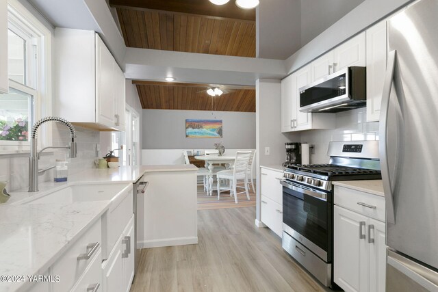 kitchen featuring light stone counters, stainless steel appliances, wood ceiling, white cabinetry, and tasteful backsplash