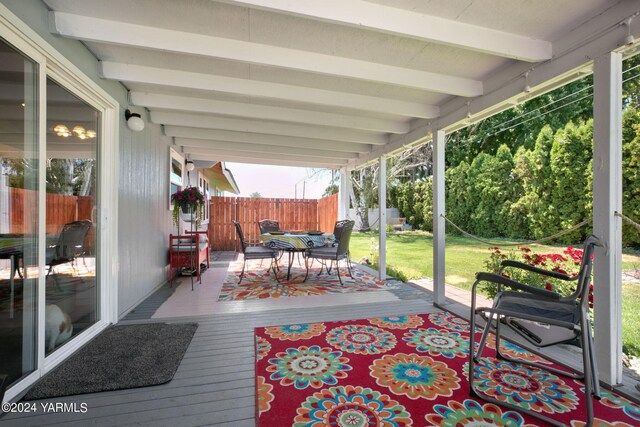 deck featuring fence, outdoor dining area, and a lawn