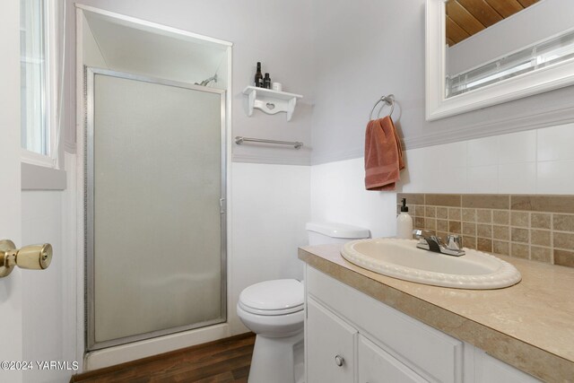 full bathroom featuring toilet, wood finished floors, vanity, a shower stall, and decorative backsplash