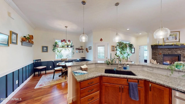 kitchen featuring wood finished floors, ornamental molding, a sink, and light stone countertops