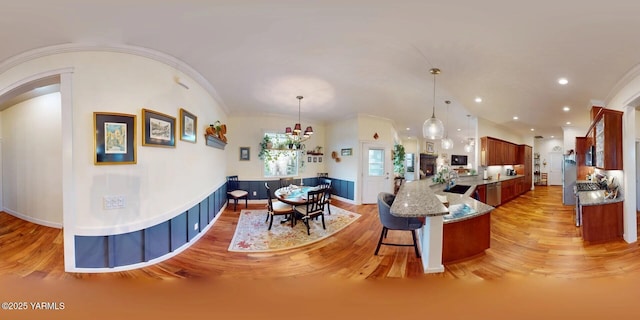 kitchen with a sink, a breakfast bar area, crown molding, and hanging light fixtures