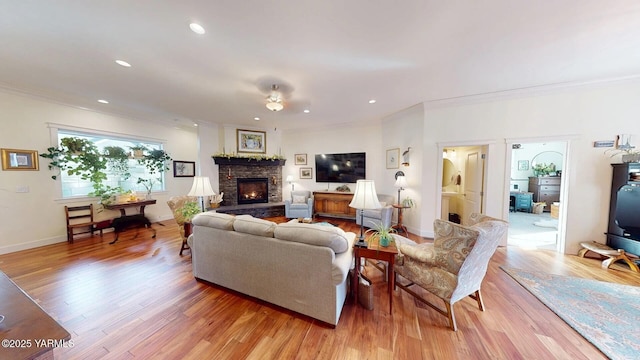 living area with light wood finished floors, recessed lighting, ornamental molding, and a stone fireplace