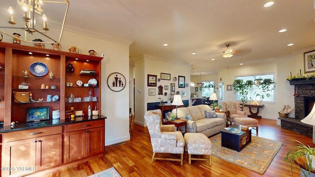 living room featuring crown molding, a fireplace, and light wood-style flooring