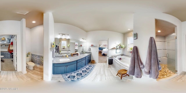 bathroom featuring lofted ceiling, toilet, a bath, double vanity, and a stall shower