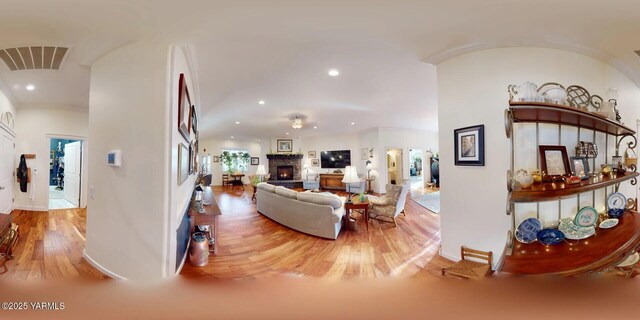 living area with visible vents, wood finished floors, crown molding, a fireplace, and recessed lighting