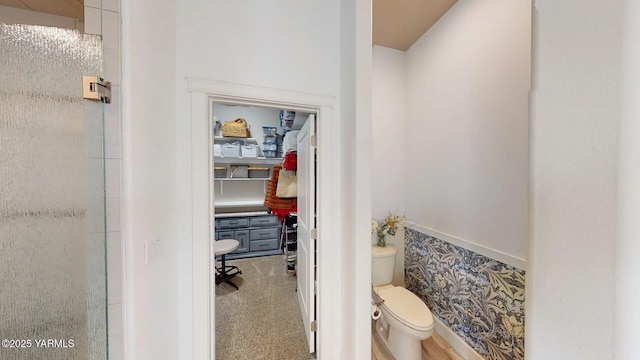 bathroom featuring a shower with shower door and toilet