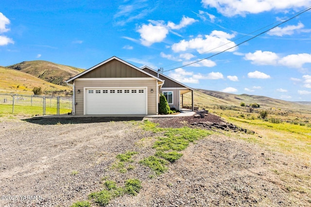ranch-style home featuring fence, a mountain view, a garage, board and batten siding, and driveway