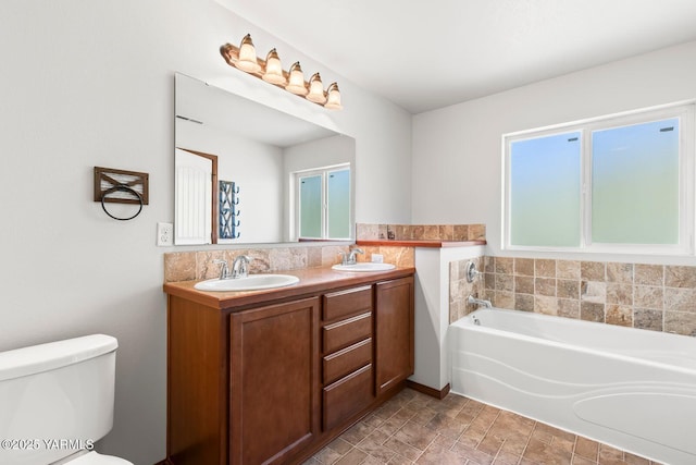 bathroom with toilet, a bath, double vanity, and plenty of natural light