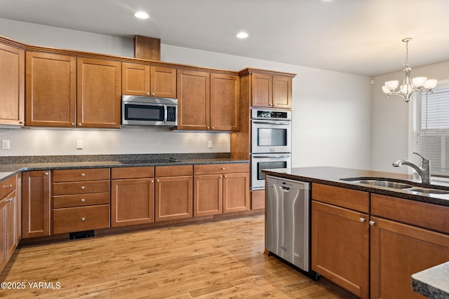 1008 S 91st Ave, Yakima, WA 98908 - kitchen featuring appliances with stainless steel finishes, brown cabinetry, a sink, light wood-style floors, and pendant lighting
