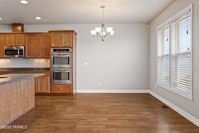 1008 S 91st Ave, Yakima, WA 98908 - kitchen featuring appliances with stainless steel finishes, wood finished floors, dark countertops, a chandelier, and recessed lighting