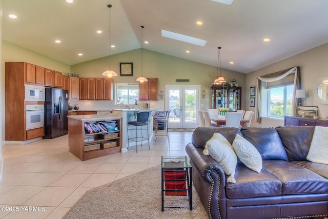 living room featuring french doors, light tile patterned flooring, a skylight, and a wealth of natural light