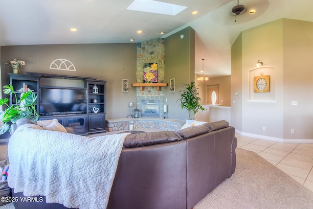 living room featuring high vaulted ceiling, a stone fireplace, light tile patterned flooring, a skylight, and baseboards