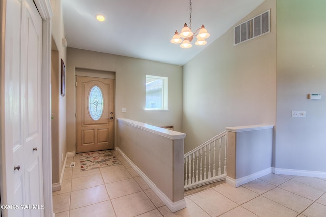 entrance foyer with light tile patterned floors, visible vents, an inviting chandelier, vaulted ceiling, and baseboards