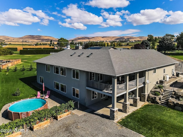 back of house with a yard, a balcony, a mountain view, and an outdoor pool