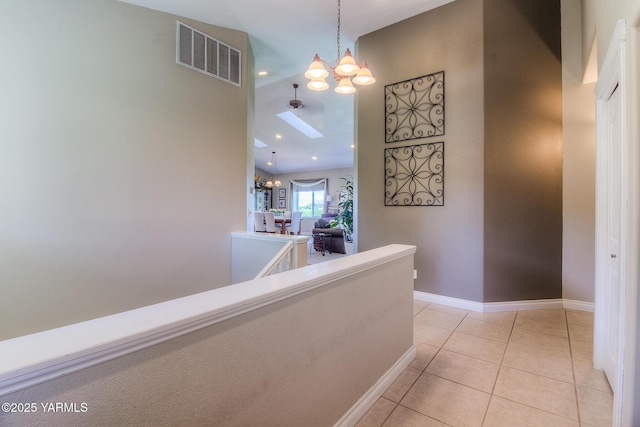 hall with a notable chandelier, visible vents, light tile patterned flooring, an upstairs landing, and baseboards