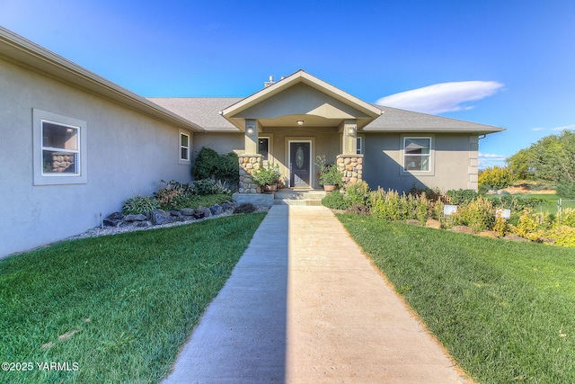 view of front of property with a shingled roof, a front yard, and stucco siding