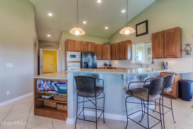 kitchen featuring white appliances, tasteful backsplash, a kitchen bar, and brown cabinetry