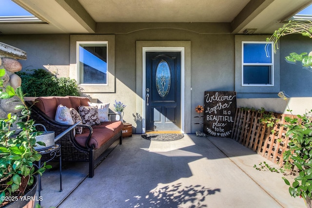 view of exterior entry featuring an outdoor hangout area, a patio, and stucco siding