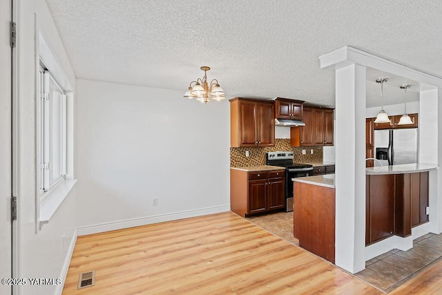 kitchen with light wood finished floors, tasteful backsplash, light countertops, visible vents, and appliances with stainless steel finishes