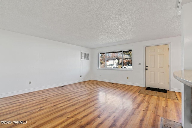 interior space featuring a textured ceiling, light wood-style flooring, and baseboards