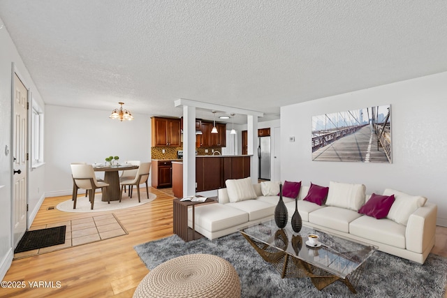 living room featuring a textured ceiling, light wood-style flooring, and a notable chandelier