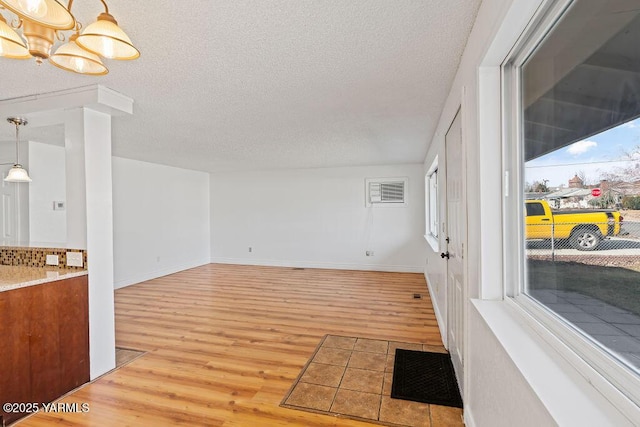 interior space with a textured ceiling, light wood finished floors, a chandelier, and baseboards