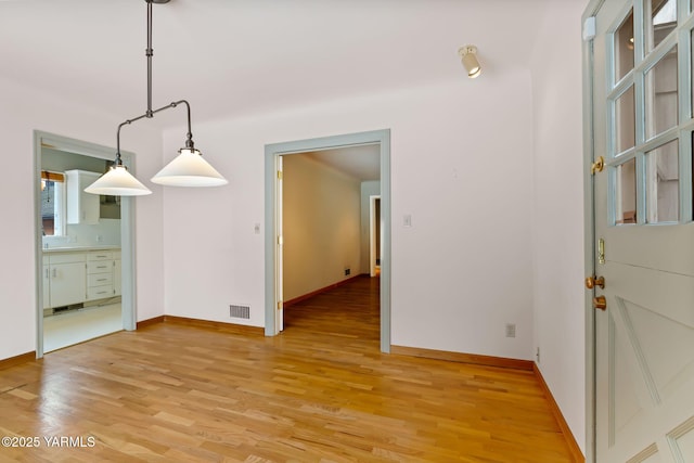 unfurnished dining area with baseboards, visible vents, and wood finished floors