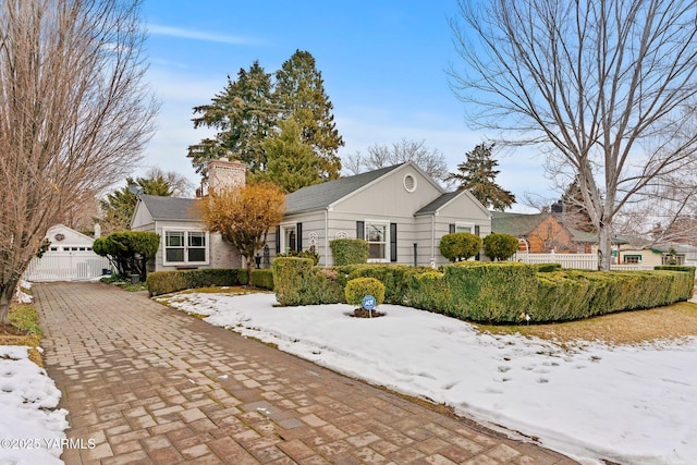 view of front facade featuring a chimney, a detached garage, and fence