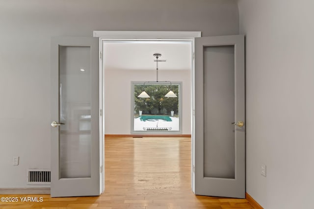 corridor with baseboards, visible vents, and light wood-style floors