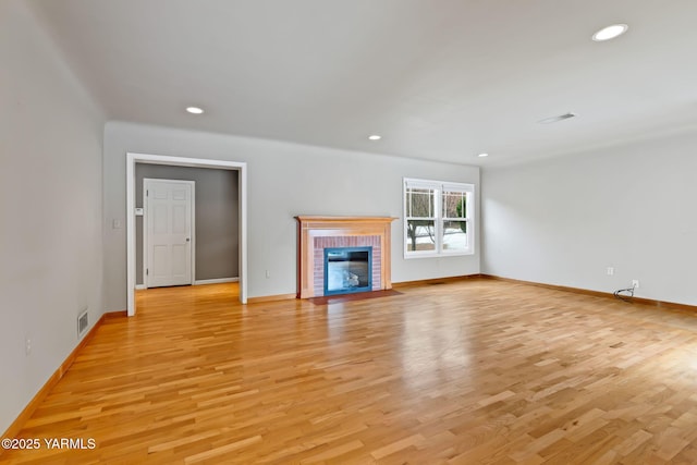 unfurnished living room featuring light wood finished floors, a fireplace, and visible vents