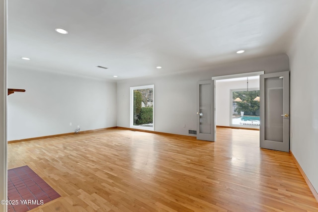 empty room featuring light wood-type flooring, visible vents, baseboards, and recessed lighting