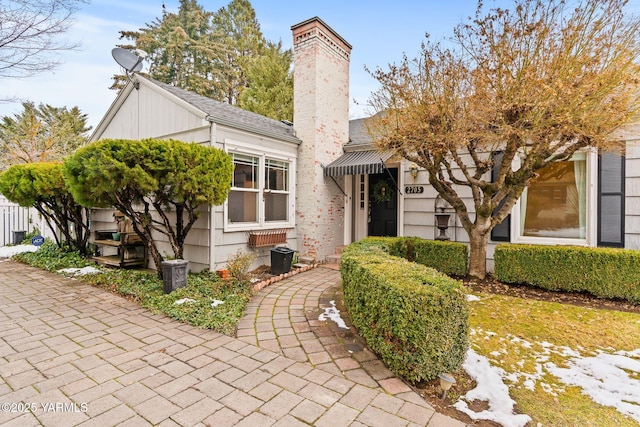 view of front of property featuring a shingled roof and a chimney