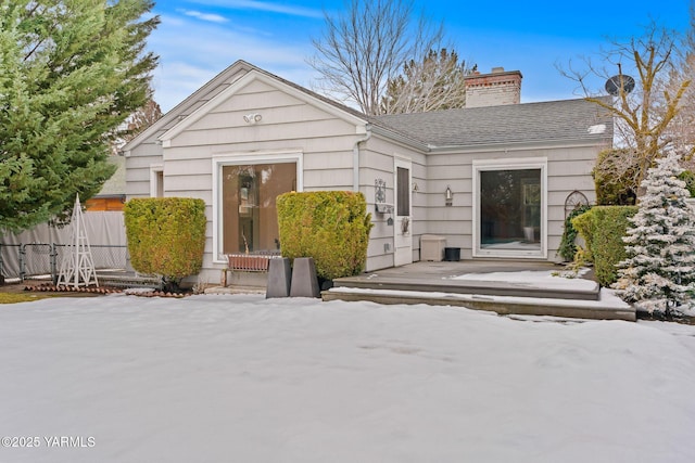 back of property featuring a shingled roof, a chimney, and fence