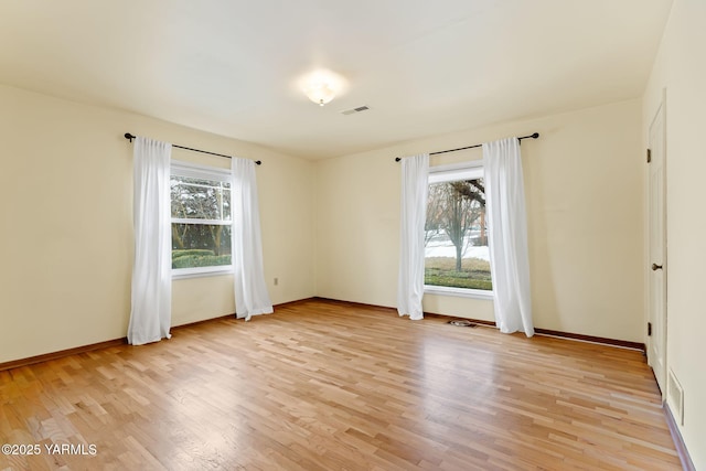 spare room with visible vents, light wood-style flooring, and baseboards