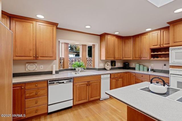 kitchen with recessed lighting, white appliances, light countertops, and a sink