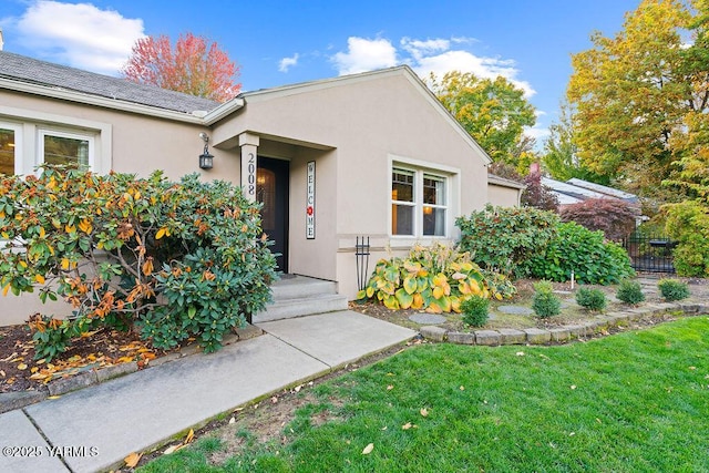 entrance to property featuring a lawn and stucco siding