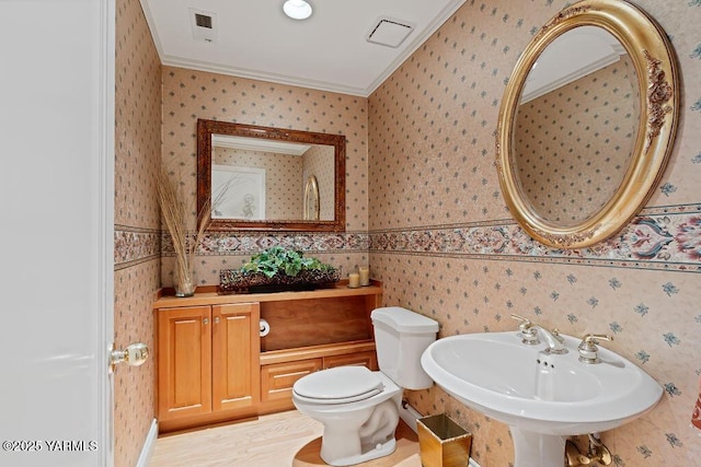 bathroom featuring ornamental molding, a sink, visible vents, and wallpapered walls