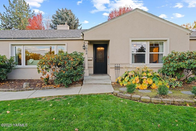 single story home with roof with shingles, a chimney, a front lawn, and stucco siding