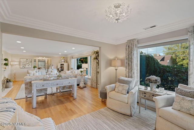 living room with a chandelier, visible vents, ornamental molding, and wood finished floors