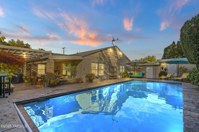 pool at dusk with a patio, a pergola, and an outdoor pool