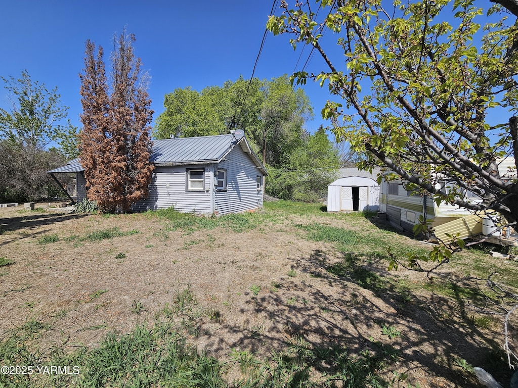 view of side of home with an outbuilding, a storage unit, and metal roof